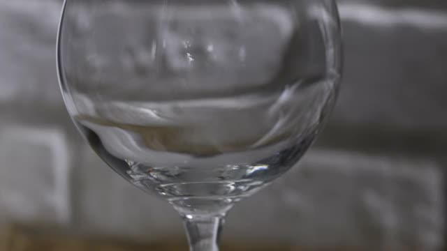 白砖墙背景上的玻璃杯里的红酒。视频素材