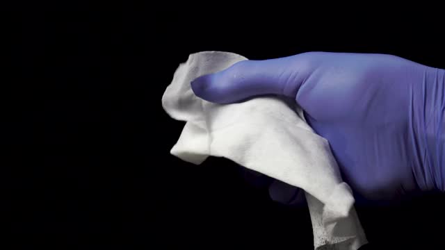手持医用手套，用湿纸巾擦在黑色背景上视频下载