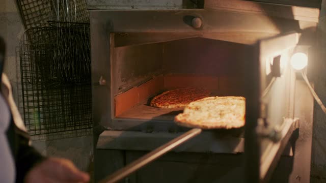 把刚烤好的披萨从烤箱里拿出来视频素材