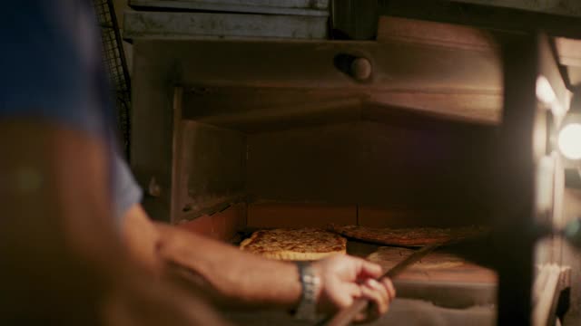 厨师在热烤箱中重新排列披萨视频素材