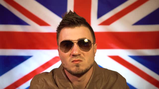 一个朋克的肖像穿着皮夹克和一个莫霍克在英国国旗的背景。英国球迷，人渣。视频下载