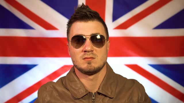 英国朋克的肖像在皮夹克与莫霍克在他的头，戴眼镜的背景英国国旗视频下载