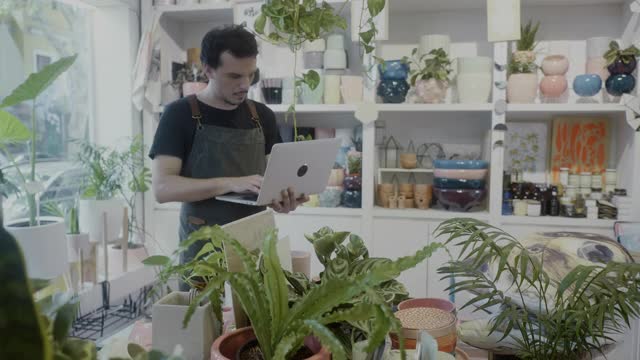 小企业主在他的植物精品店检查笔记本电脑库存视频素材