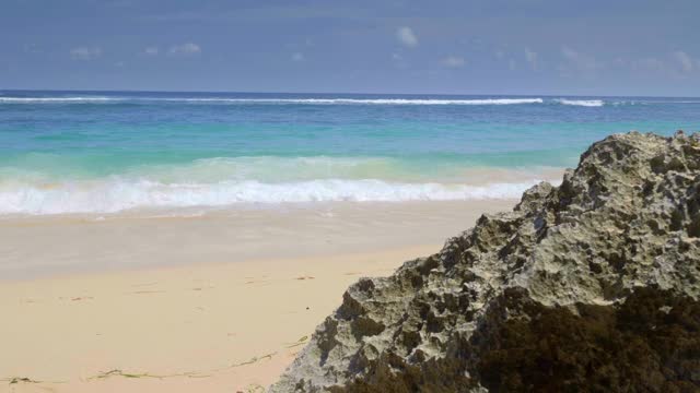 一个手持运动美丽生动的热带海滩与蓝色的海浪拍打沙子在慢动作视频下载
