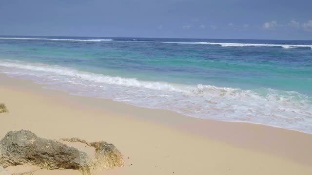 一个缓慢的热带沙滩与岩石和巨浪与泡沫的手持式拍摄视频下载