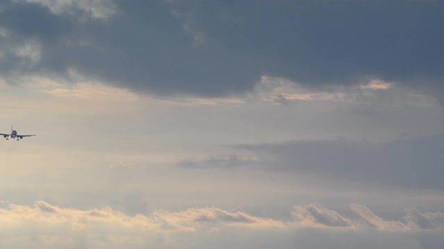 喷气式飞机的特写是降落在日落天空与蓝色戏剧性的云视频下载
