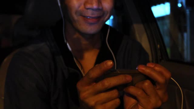 4K，亚洲男人在车里看智能手机视频素材
