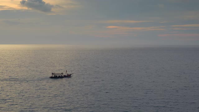 在美丽的日落天空和飞机降落的背景下，一艘小船和人们的剪影在海里游泳视频下载