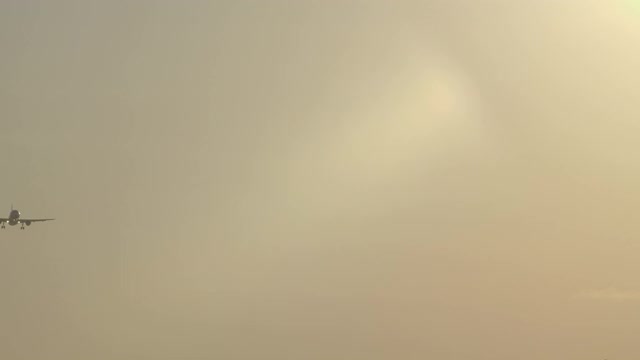一架小型民用喷气式飞机的剪影在刮风的天气里降落在美丽的黄色日落视频下载