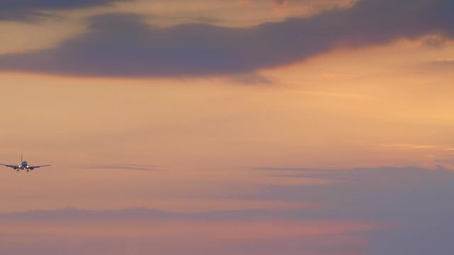 黄色和紫色的晚霞中，一架小型喷气式飞机的剪影正在机场降落视频下载