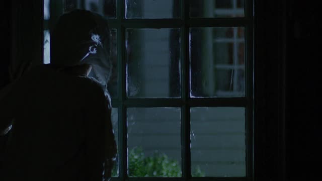 一个年轻女子在夜晚望着窗外的中等镜头视频下载