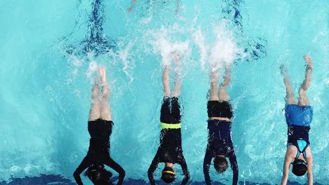 在游泳教练的指导下，亚洲中国游泳运动员在泳池边练习用腿泼水视频素材