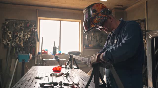 在车间使用焊枪工作时戴焊接头盔的中年焊工视频素材