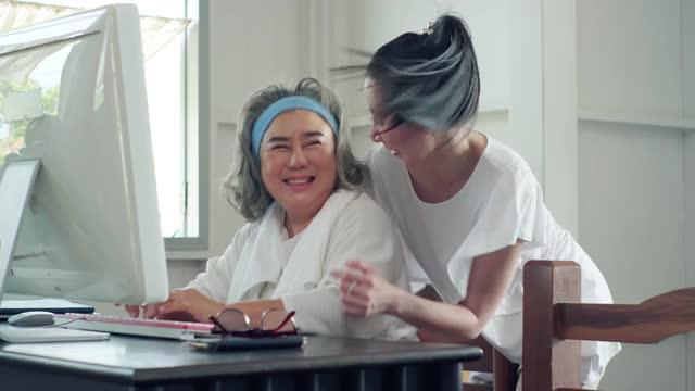 一位老年妇女和她的女儿坐在家里的沙发上使用电脑。视频素材