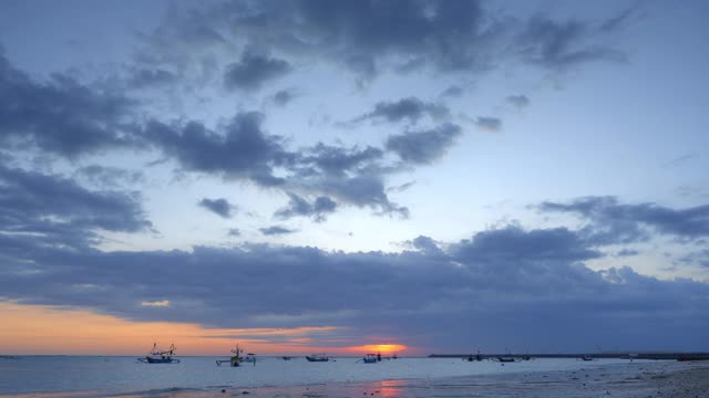 传统的巴厘渔民在机场附近美丽多彩的蓝天和红日的日落海滩上捕鱼视频下载