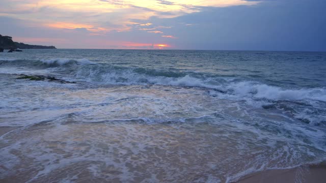 黄昏的海滩与黑色的水和大波浪与泡沫的沙滩和日落的天空视频下载