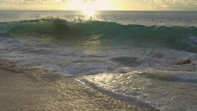日落时，海滩附近有岩石和海藻，涨潮时海浪会很大视频下载