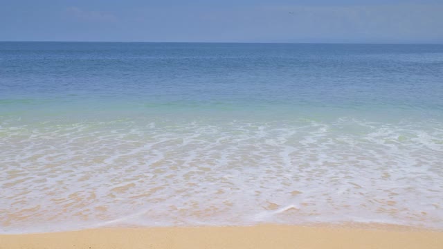 蔚蓝的海洋与巨大的温暖的海浪和浪花从沙滩下干净的蓝色天空和飞机降落在背景视频下载