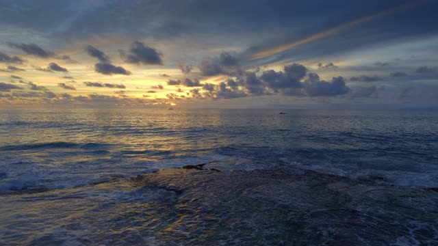 在美丽的日落与船剪影在深蓝色的海洋热带海滩上的高潮波浪视频下载