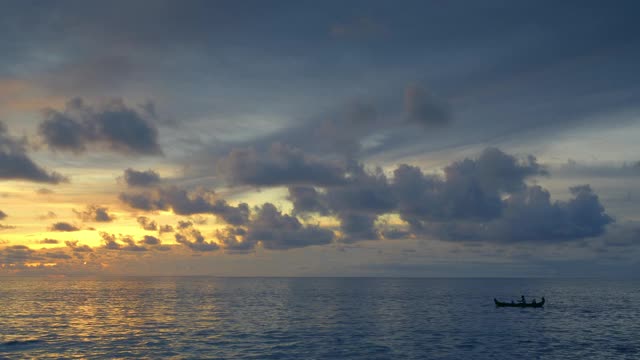 日落后，一艘传统的小木船在深蓝色的海面上漂浮着渔夫的剪影视频下载