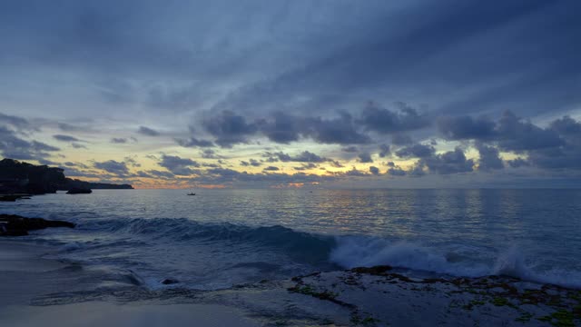 一个海湾的全景与小渔船的剪影在深蓝色的水与高潮浪和溅在日落后视频下载