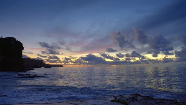 岩石海滩与高潮波和日落后深蓝色的水在热带岛屿与岩石视频下载