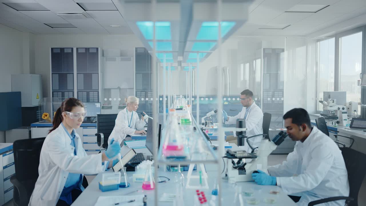现代医学研究实验室:多元化的科学家团队使用移液管，分析生物化学样品，谈话。医学科学实验室，微生物学发展。先进的设备视频素材