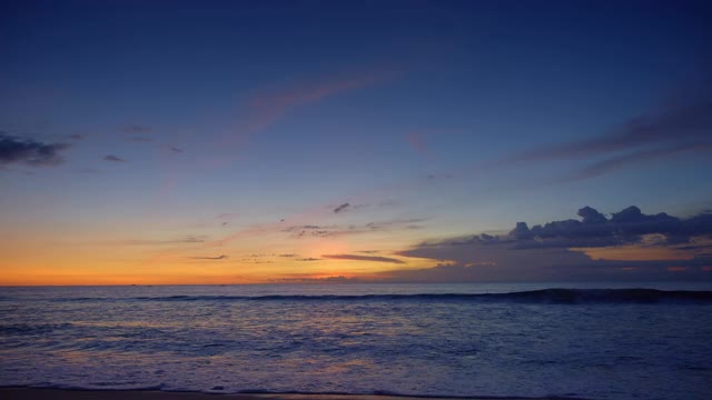 日落后，热带岛屿上深蓝色的海洋和大浪，鲜艳的黄色和红色的天空视频下载
