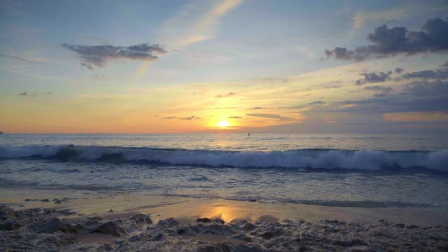 在美丽的彩色日落期间，巨大的海浪在热带海滩与深蓝色的水的缓慢运动视频下载