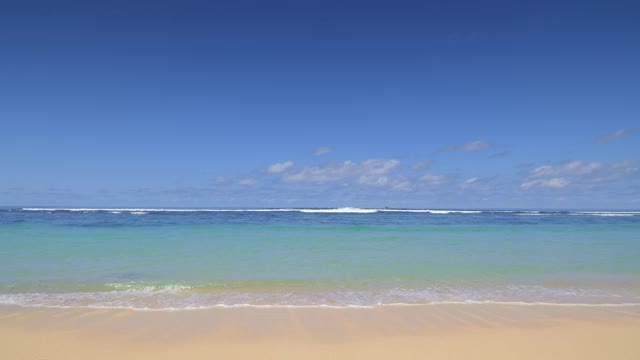 在温暖的下午，充满活力的蓝色和青色的海水和沙滩附近的小波浪视频下载