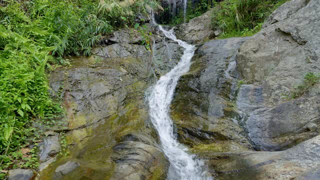 瀑布从岩石在绿色雨林视频素材