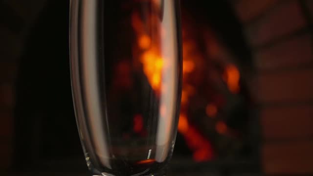 一波香槟酒流入火背景下的一个高脚杯视频下载