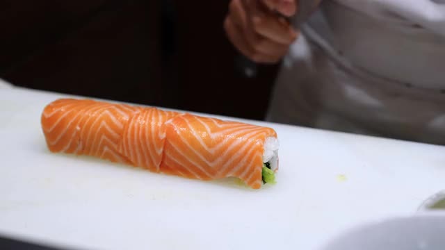 4K专业厨师用厨房刀切三文鱼和虾天妇罗寿司卷。男厨师在日本料理中准备健康食物菜单，米饭和海鲜寿司卷。视频素材