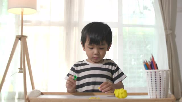 蹒跚学步的小男孩在玩粘土视频素材