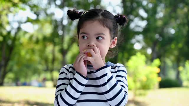亚洲小女孩在公园里吃包子视频素材