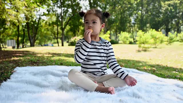 亚洲小女孩在公园里吃包子视频素材