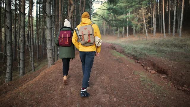 在秋天的一天，一对年轻夫妇背着背包一起徒步旅行视频素材