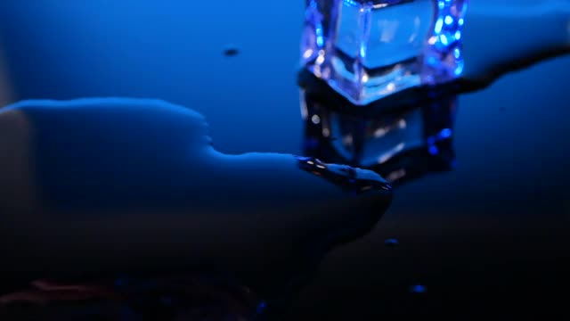 蓝色背景上的玻璃表面上的冰块视频素材