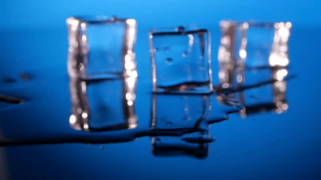 蓝色背景上的玻璃表面上的冰块视频素材