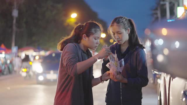 亚洲朋友喜欢在夜市喂烤鱿鱼。泰国的街头食品。视频下载