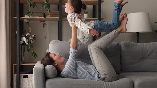 女人躺在客厅的沙发上和女儿玩耍视频素材