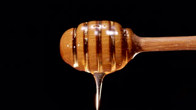 蜂蜜从木勺上滴落在黑色背景上视频素材