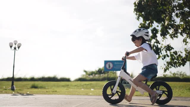 女孩骑平衡自行车和有乐趣的骑自行车与运动头盔视频素材