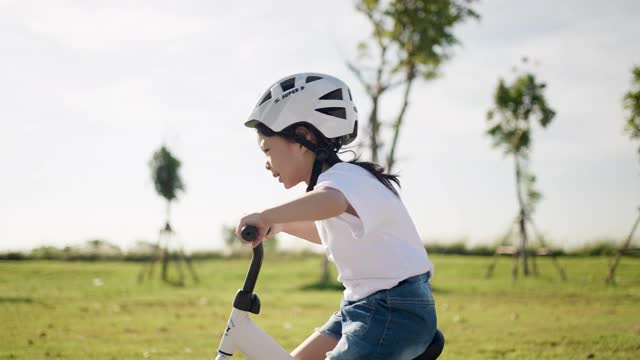 女孩骑平衡自行车和有乐趣的骑自行车与运动头盔视频素材