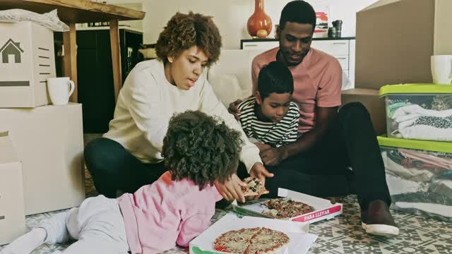 加勒比黑人家庭在搬家日享受披萨休息时间视频下载