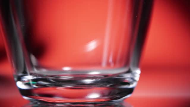 将可乐倒入红色背景的玻璃杯中视频下载
