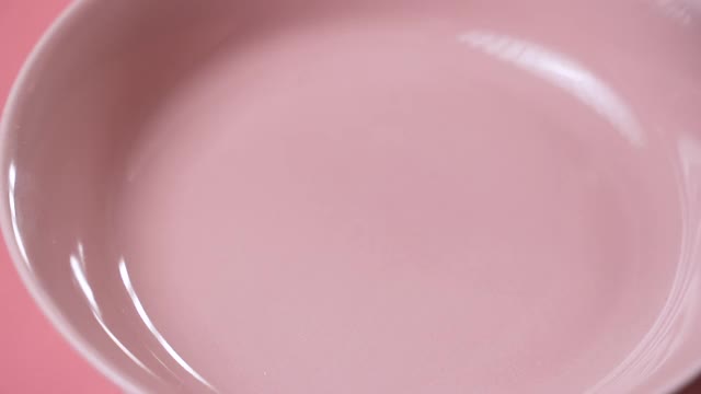 特写的脆环落入一个粉红色的盘子里视频素材