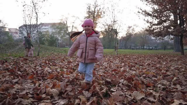 可爱好玩的5岁女孩在一个清新的秋天里穿着玫瑰色棉袄跑步视频素材