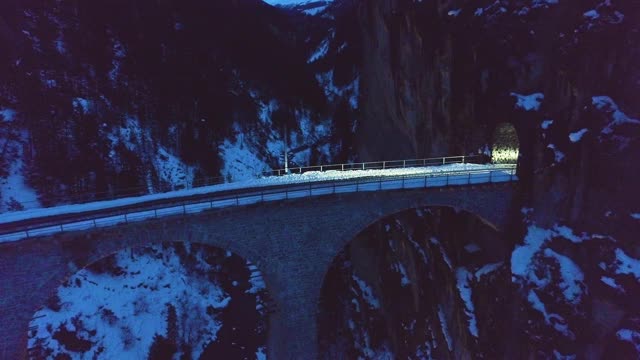 Landwasser高架桥与铁路和火车在冬季晚上。山脉、森林和河流。鸟瞰图。瑞士古老的桥梁和自然。无人机向后和向上飞行视频素材