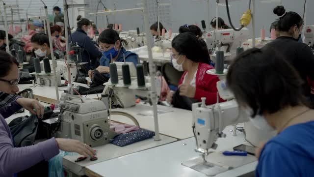 在纺织工厂的缝纫工场工作的体力女工都戴着防护口罩视频素材